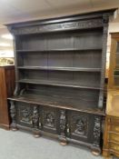 A heavily carved oak bookcase fitted with cupboards beneath