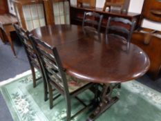 An oval oak dining table with one leaf and four ladder back chairs