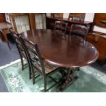 An oval oak dining table with one leaf and four ladder back chairs