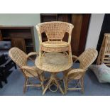 A wicker conservatory table and three similar chairs