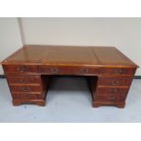 A reproduction twin pedestal writing desk and tooled leather panel top