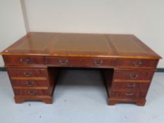 A reproduction twin pedestal writing desk and tooled leather panel top
