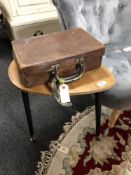 A vintage brown leather suitcase and a lamp table