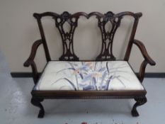 A reproduction mahogany two seater bench on claw and ball feet