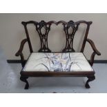 A reproduction mahogany two seater bench on claw and ball feet