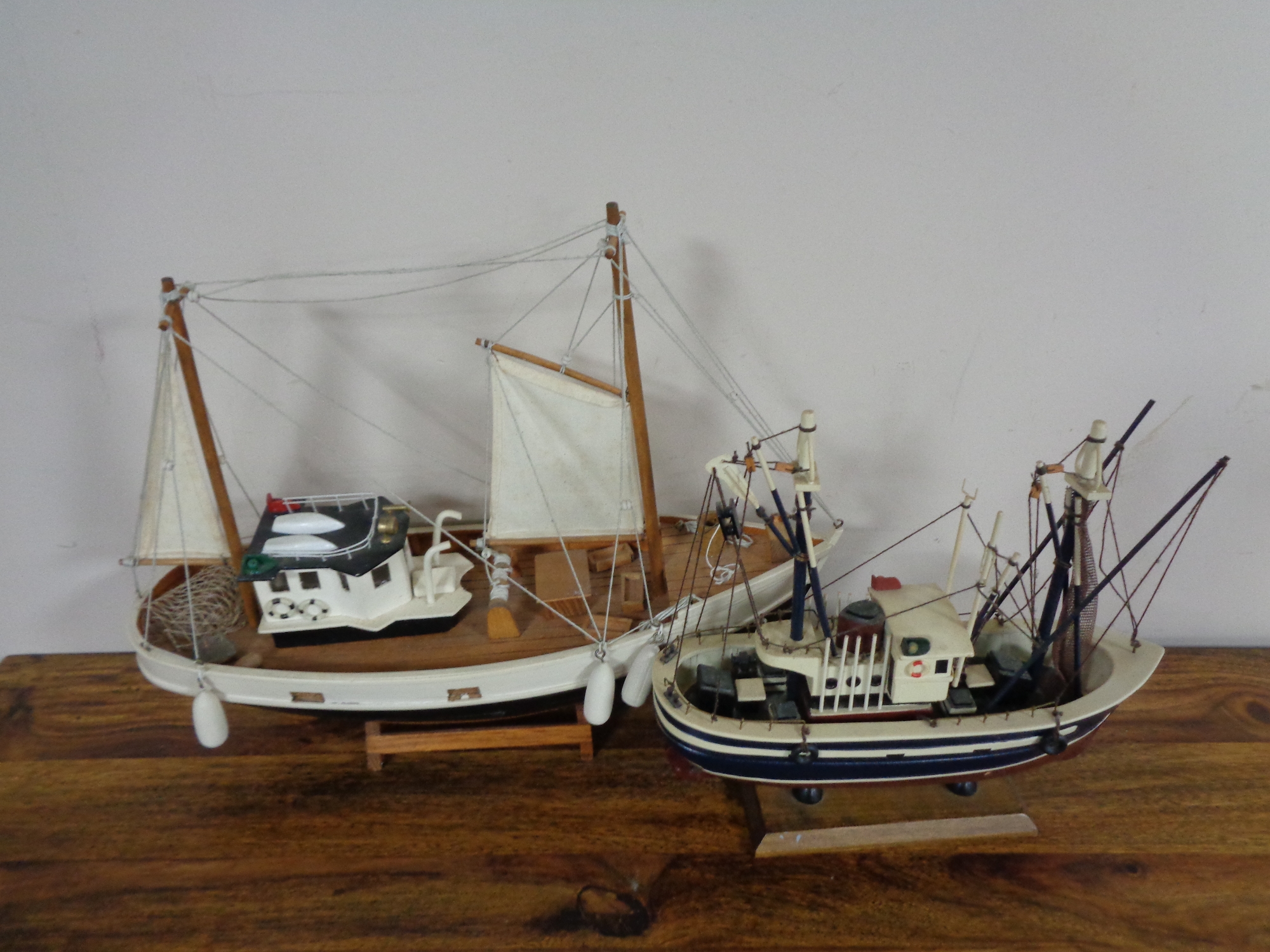 Two wooden model fishing trawlers on stand