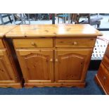 A pine double door cabinet fitted with two drawers