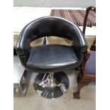 A black leather hydraulic hair dresser's chair