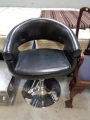 A black leather hydraulic hair dresser's chair
