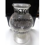 An antique glass storage jar bearing advertising