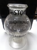 An antique glass storage jar bearing advertising