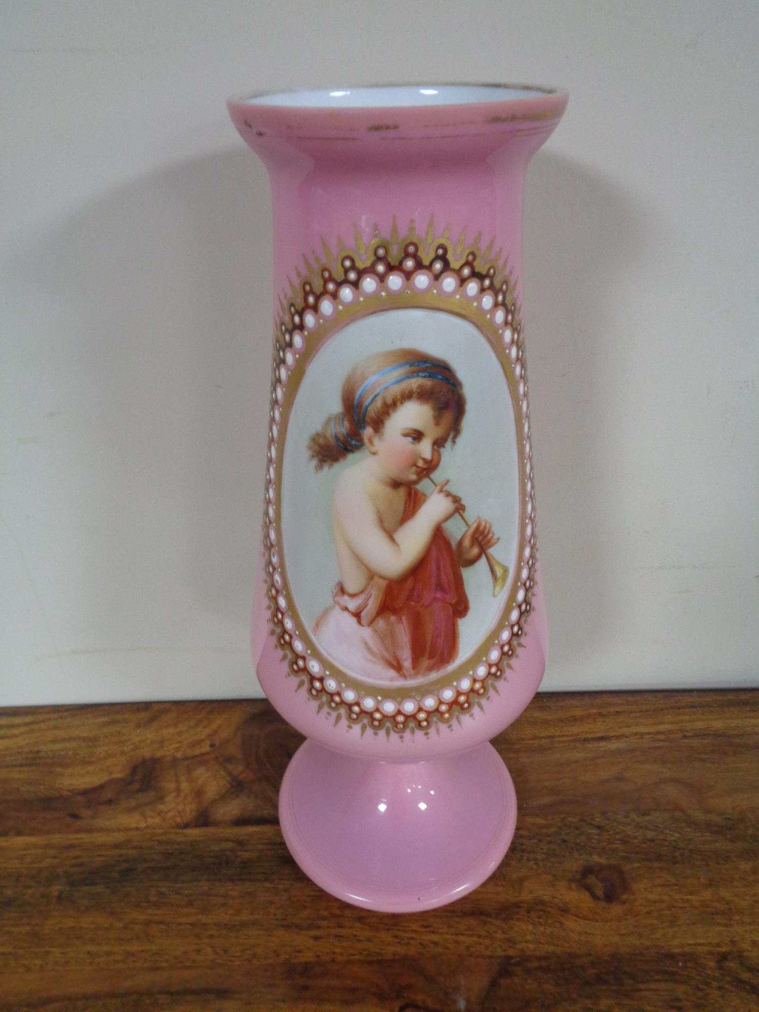 A Victorian pink glass vase with hand painted panel depicting girl with flute