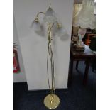 A brass three way floor lamp with glass shades