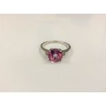 A silver dress ring set with a pink stone,