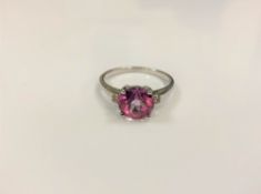 A silver dress ring set with a pink stone,