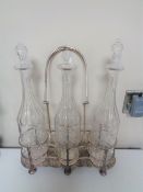 A silver plated three bottle Tantalus on raised feet with three glass decanters