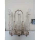 A silver plated three bottle Tantalus on raised feet with three glass decanters