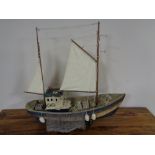 A wooden model of a fishing trawler on wooden stand