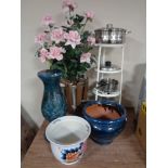 A cast iron four tier pan stand containing aluminium pans, plant in pot,
