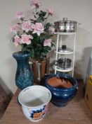 A cast iron four tier pan stand containing aluminium pans, plant in pot,