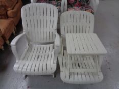 A pair of white plastic folding garden chairs and table