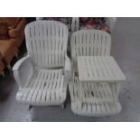 A pair of white plastic folding garden chairs and table