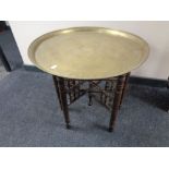 An Eastern brass topped table on folding base