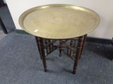 An Eastern brass topped table on folding base