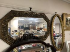 An octagonal brass embossed framed mirror together with an oval gilt framed mirror
