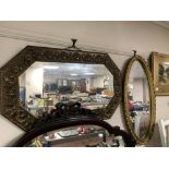 An octagonal brass embossed framed mirror together with an oval gilt framed mirror