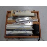 A wooden box of assorted rulers and measures,