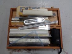 A wooden box of assorted rulers and measures,