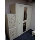 A cream and gilt triple door wardrobe together with three drawer bedside chest
