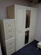 A cream and gilt triple door wardrobe together with three drawer bedside chest