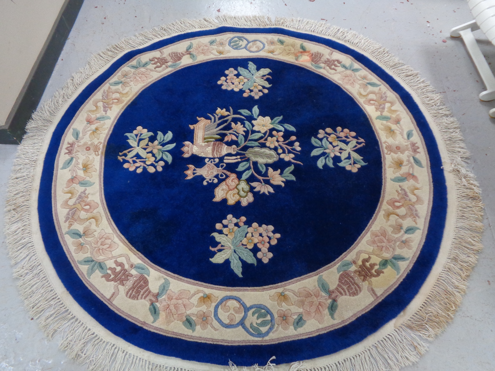 A circular fringed Chinese rug on blue ground