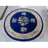 A circular fringed Chinese rug on blue ground