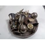A circular plated tray containing servers and cutlery, plated goblets,