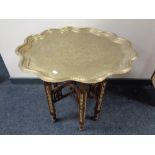 A Moorish brass topped table on folding wooden base