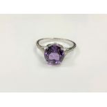A silver dress ring set with a purple stone,
