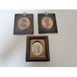 Two George III silhouette type miniatures together with a further portrait miniature behind glass.