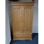 A pine double door wardrobe fitted with a drawer beneath