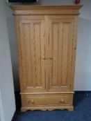 A pine double door wardrobe fitted with a drawer beneath