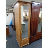 A narrow pine mirrored cupboard fitted with shelves and drawers beneath. 185 cm x 54.5 cm x 61.5 cm.