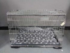 A folding black metal dog cage, height 52 cm, width 82 cm, depth 50 cm.