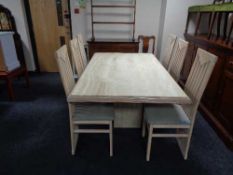 A contemporary dining table with travertine inset panel and set of six high backed chairs in washed