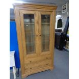 A contemporary oak double door glazed cabinet fitted with two drawers
