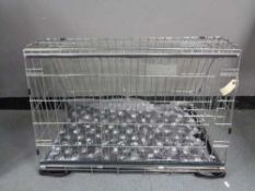 A folding black metal dog cage, height 52 cm, width 82 cm, depth 50 cm.