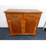 An inlaid yew wood double door cabinet fitted with two drawers above