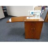 A twentieth century walnut sewing cabinet with Singer sewing machine and accessories