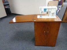 A twentieth century walnut sewing cabinet with Singer sewing machine and accessories